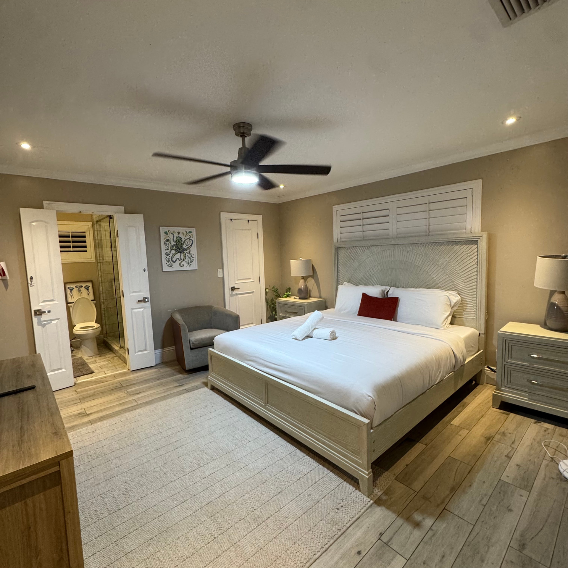 Freshly cleaned master bedroom with made king bed and rolled towels